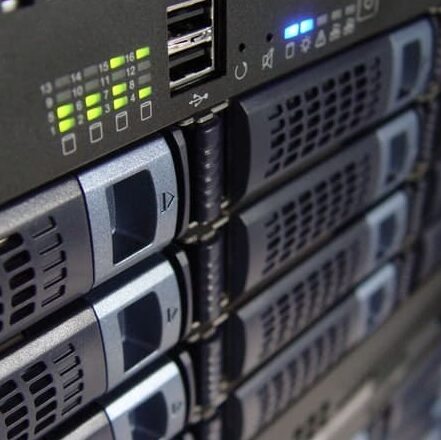 Close-up of the front panel of a server rack showing multiple hard drive bays, indicator lights, USB ports, and ventilation grilles. Close-up of the front panel of a server rack showing multiple hard drive bays, indicator lights, USB ports, and ventilation grilles.